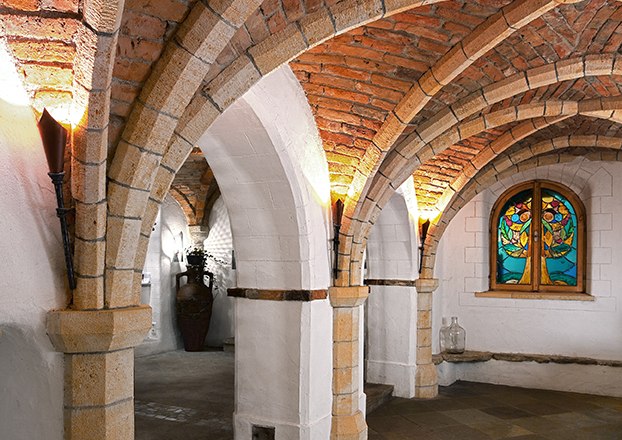 Vaulted cellar with brick arches and stained glass windows.