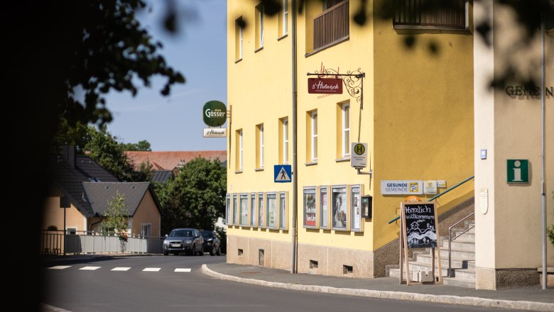 Yellow building next to road and crosswalk, with steps and s'Hutwisch sign.