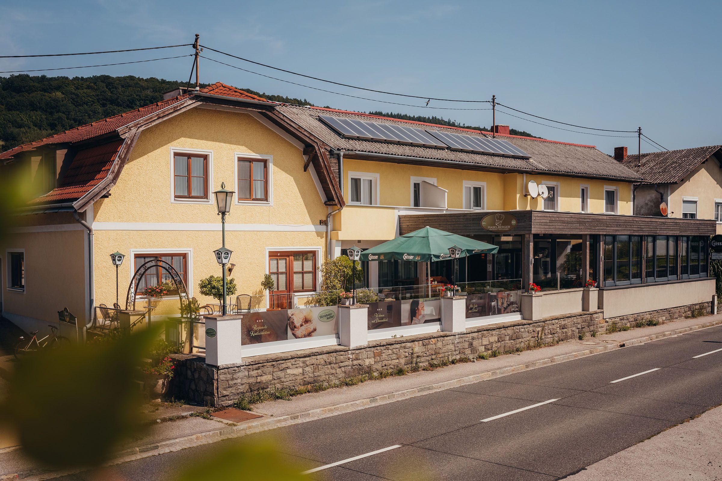 Yellow inn with terrace and parasols on a country road.
