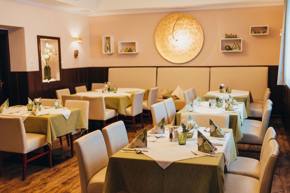 Elegant restaurant with laid tables and green tablecloths.