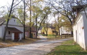 A quiet village square with small, traditional buildings and trees in the fall.