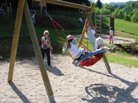 Children swinging in a nest swing on a playground.