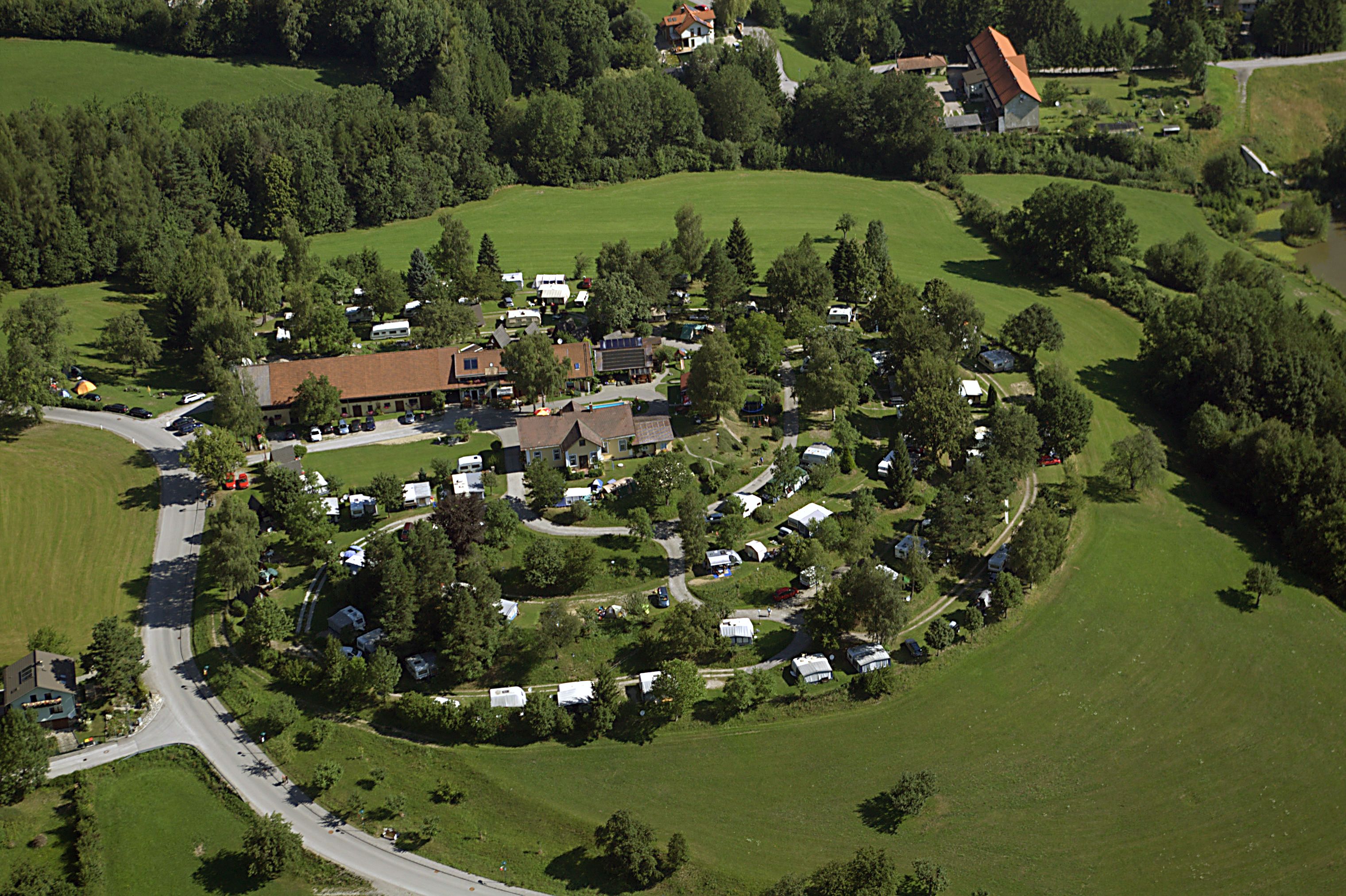 Aerial view of a campsite in the middle of a green landscape with caravans and tents.