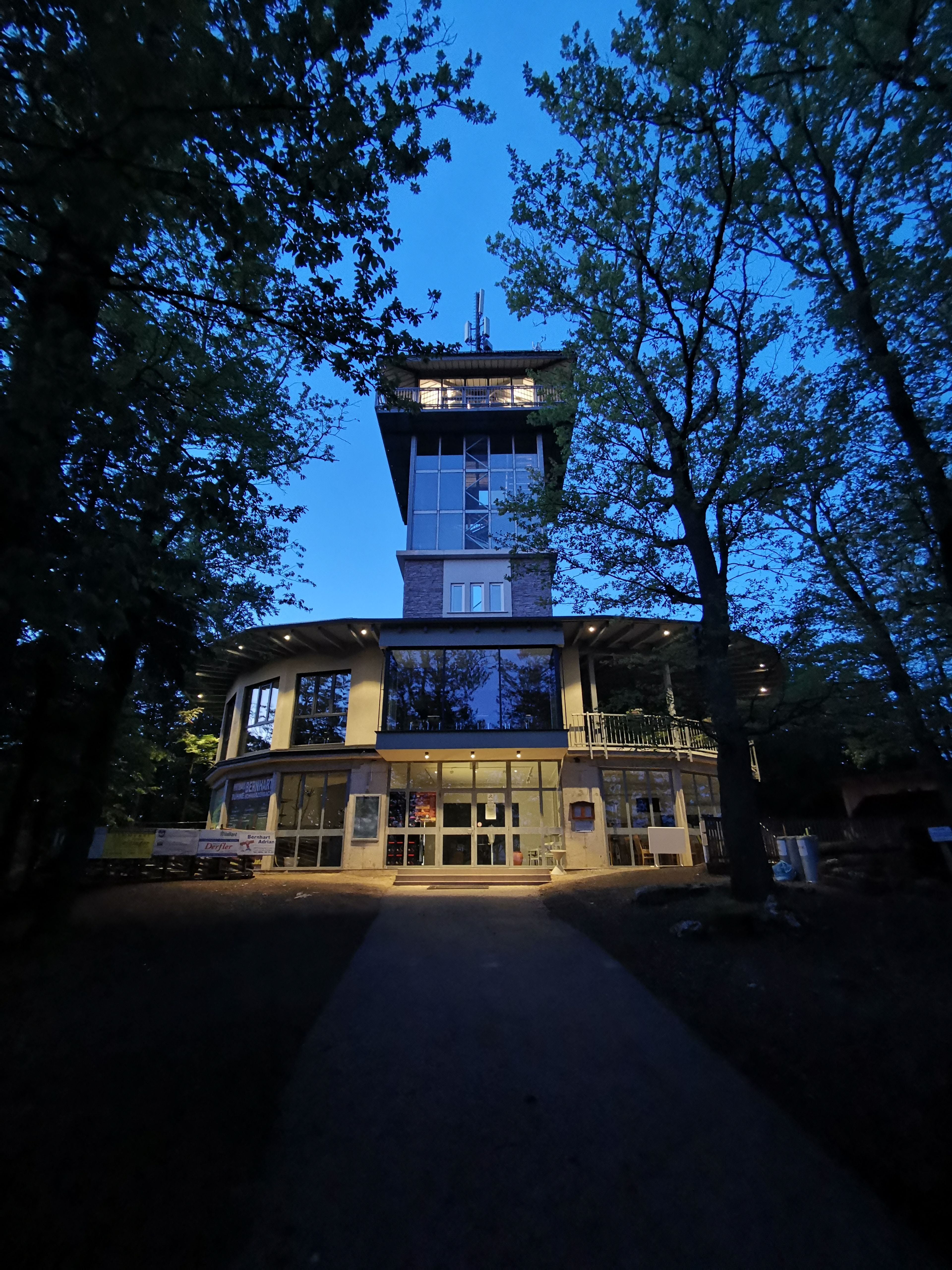 Oval building with glass observation tower at night.