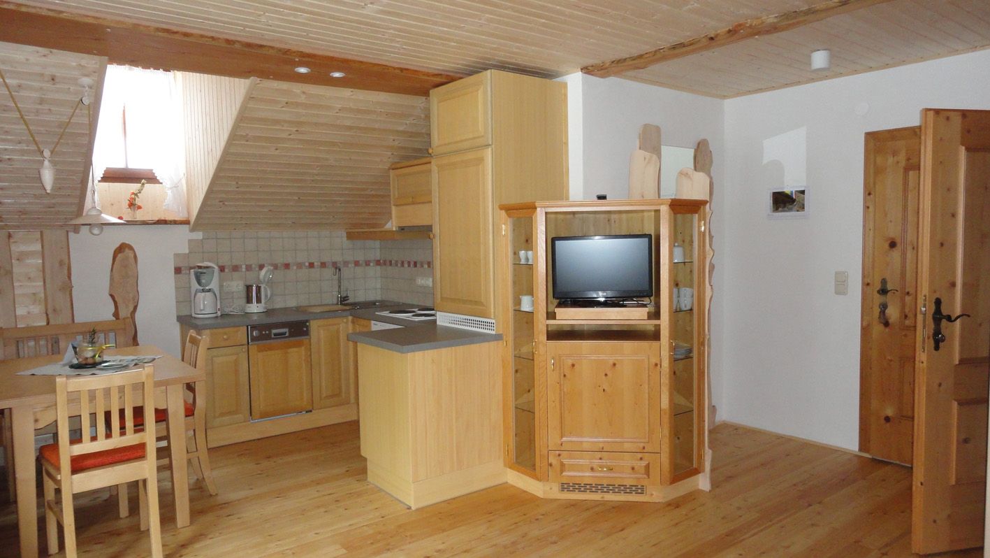 Cozy attic apartment with wooden furniture, kitchenette and dining table.