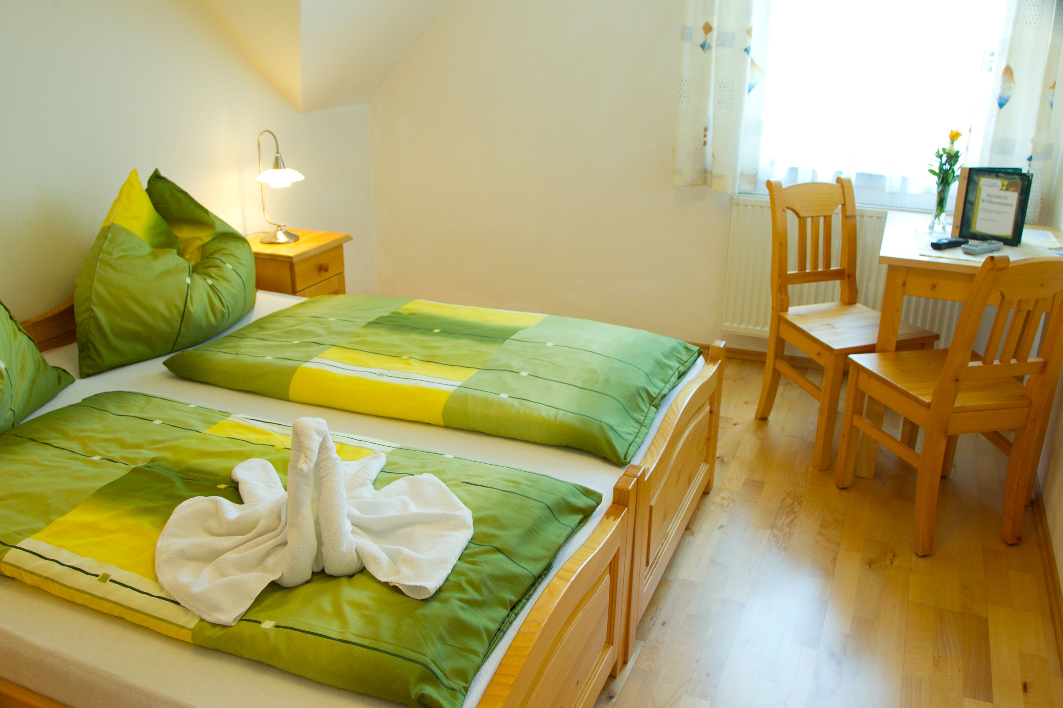 Cozy guest room with double bed, green bed linen and wooden furniture.
