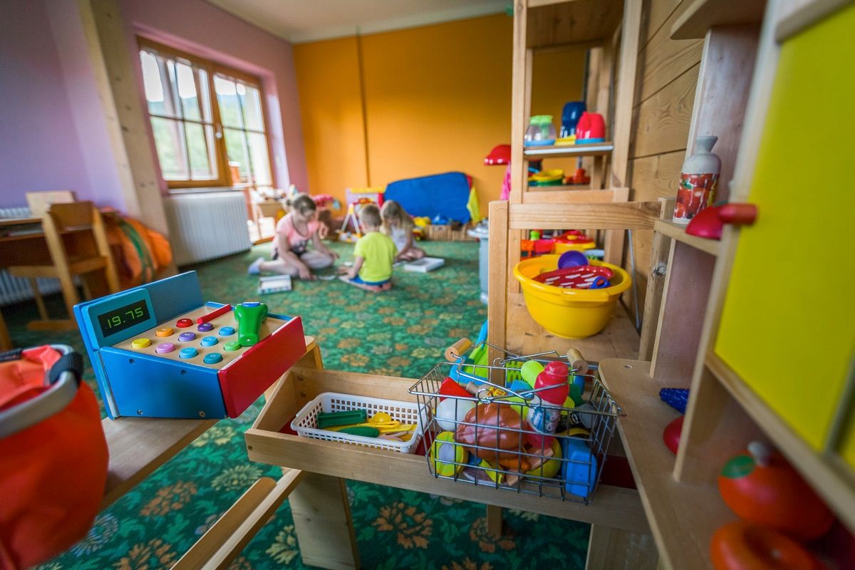 Playroom with colorful toys and children in the background.