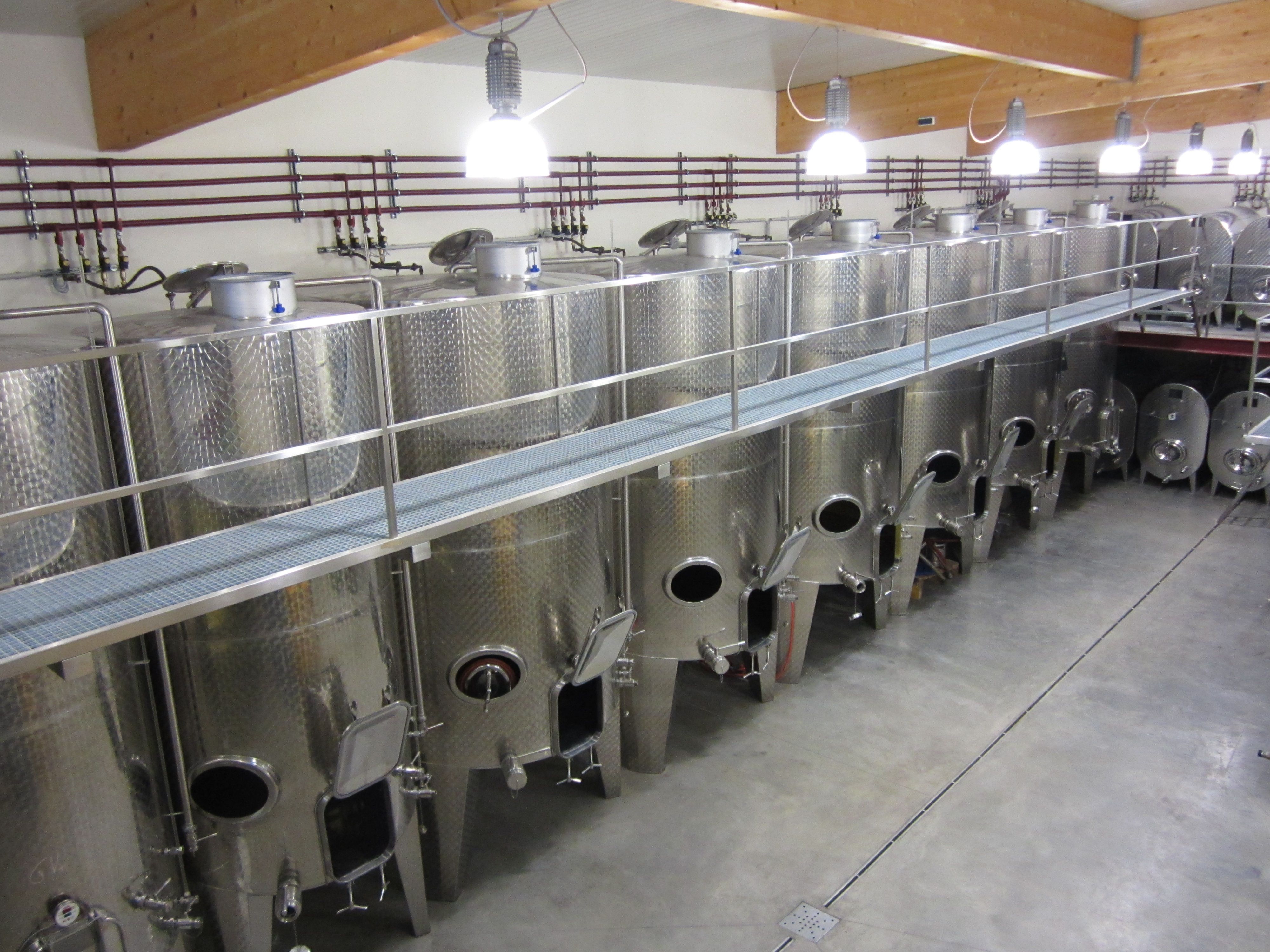 Row of large stainless steel tanks in a modern winery.