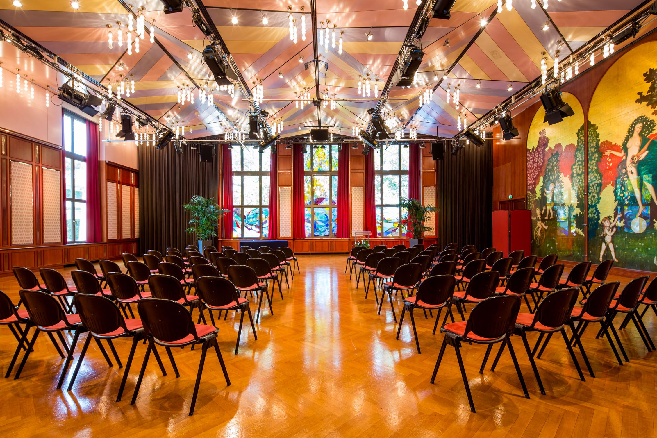 Interior view of the Casineum in the Congress Center Baden with rows of chairs and colorful wall decorations.