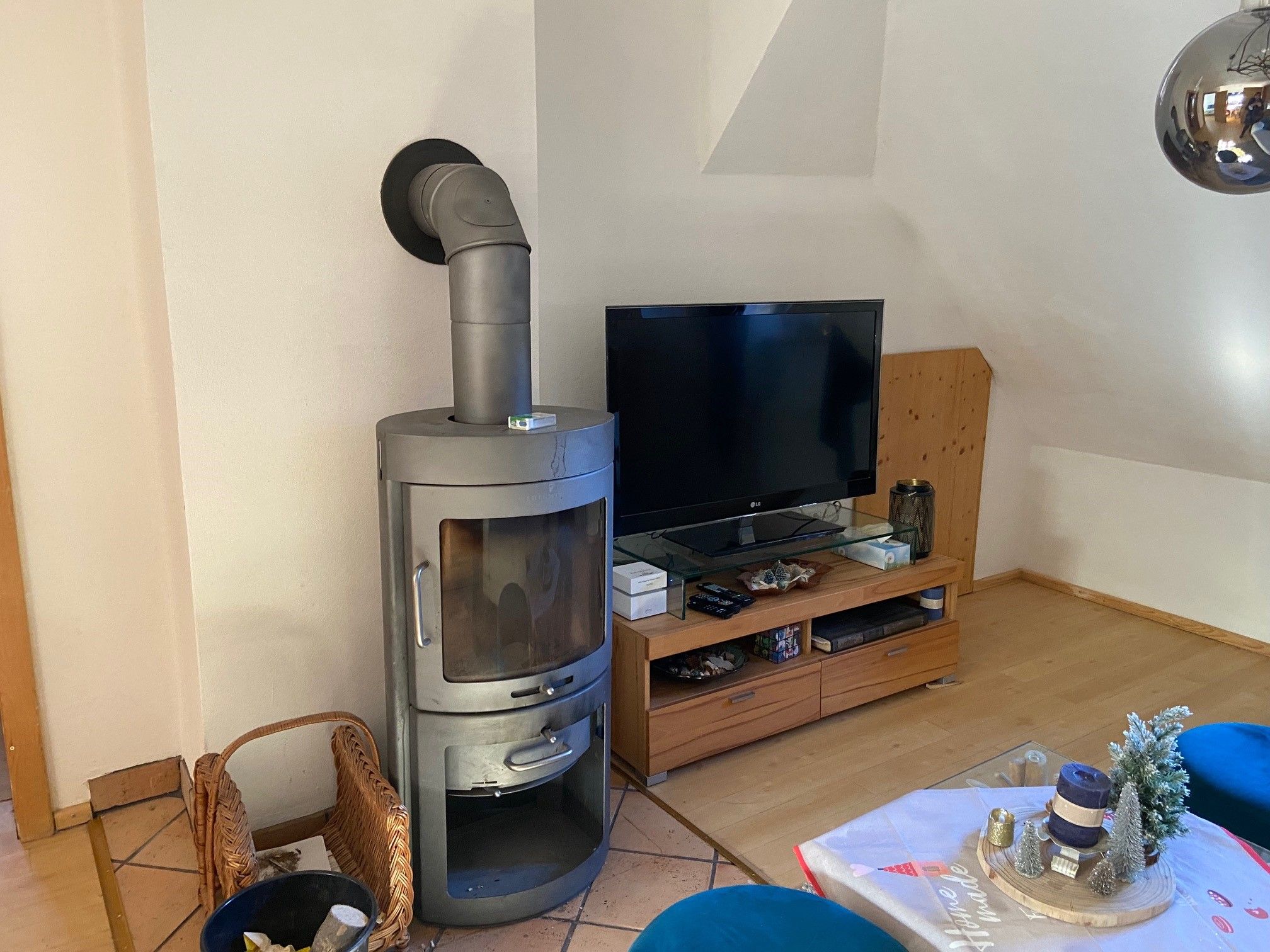 Living room with wood-burning stove, TV and decorated table.