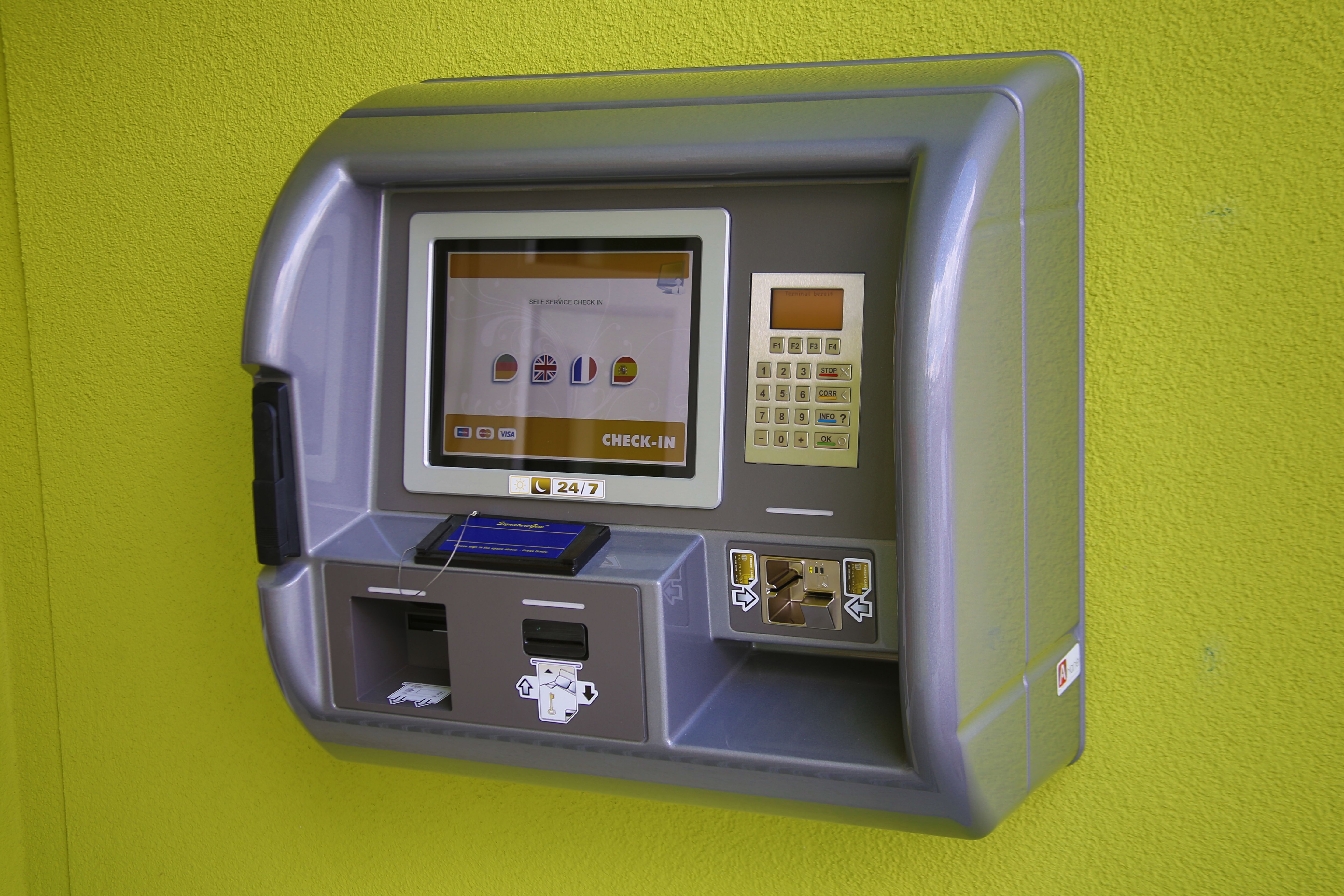 A check-in machine on a green wall.