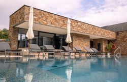 Exterior view of a modern hotel with pool and sun loungers.
