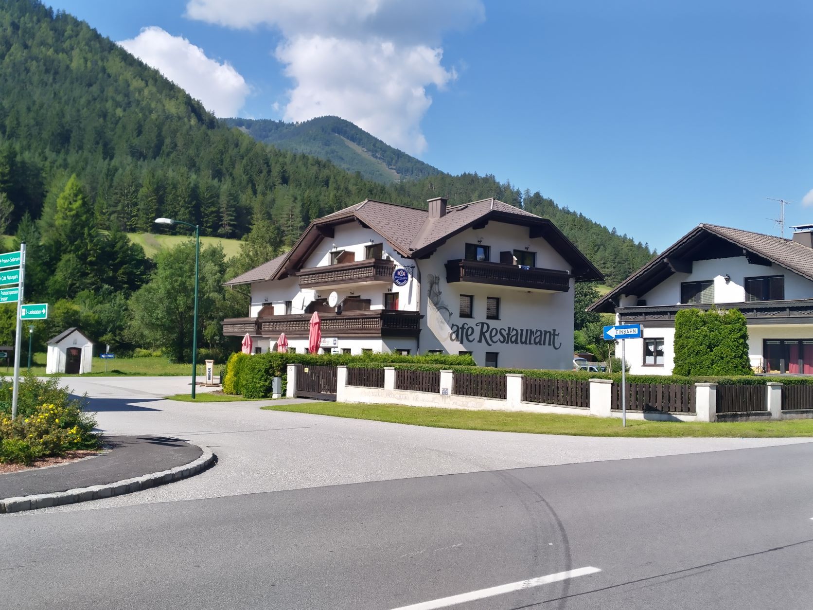A café-restaurant in a rural area with mountains in the background.