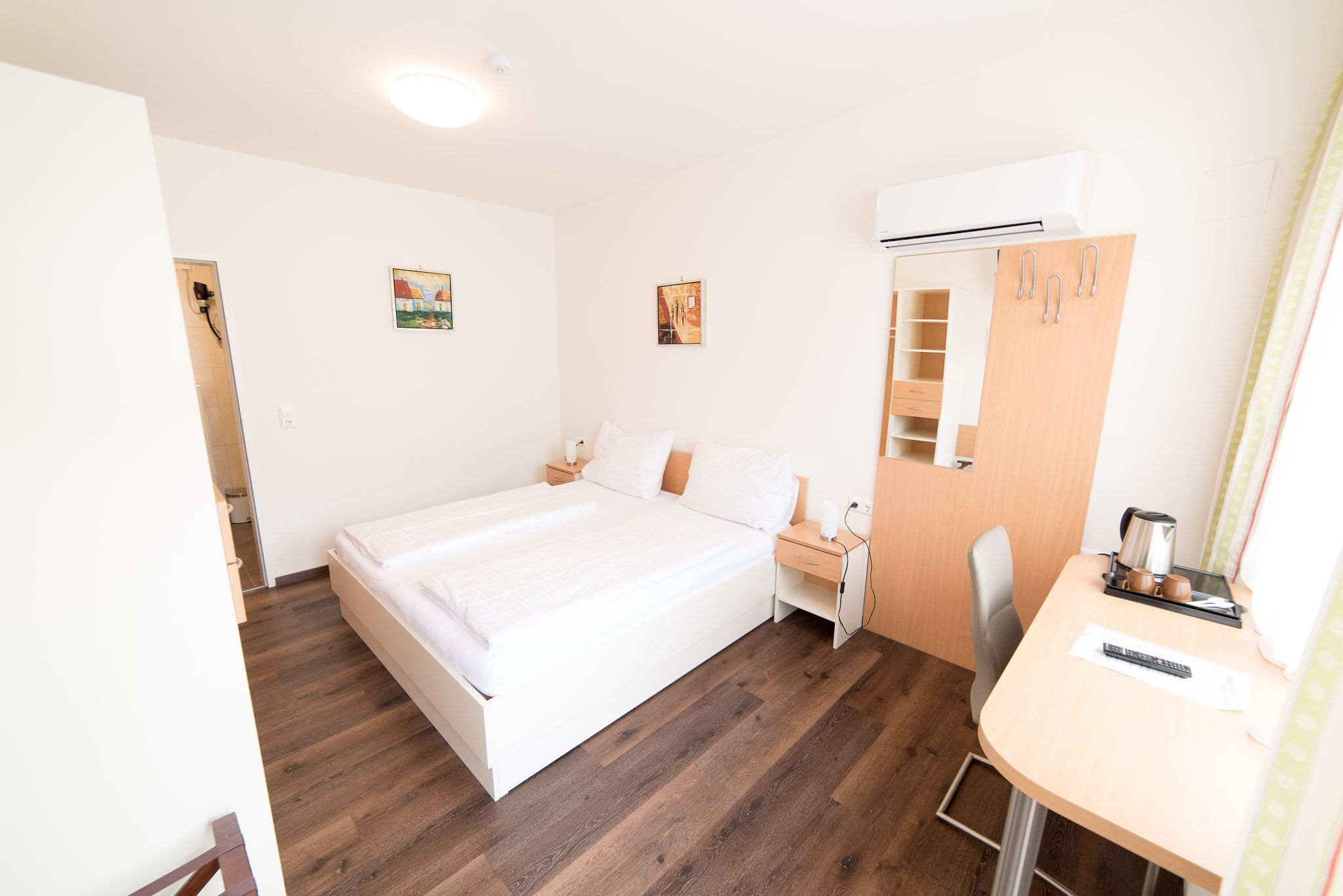 Bright bedroom with wardrobe, double bed, bedside table, desk.