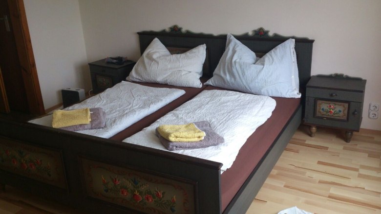 A traditionally decorated double bed with two bedside tables in a bedroom.