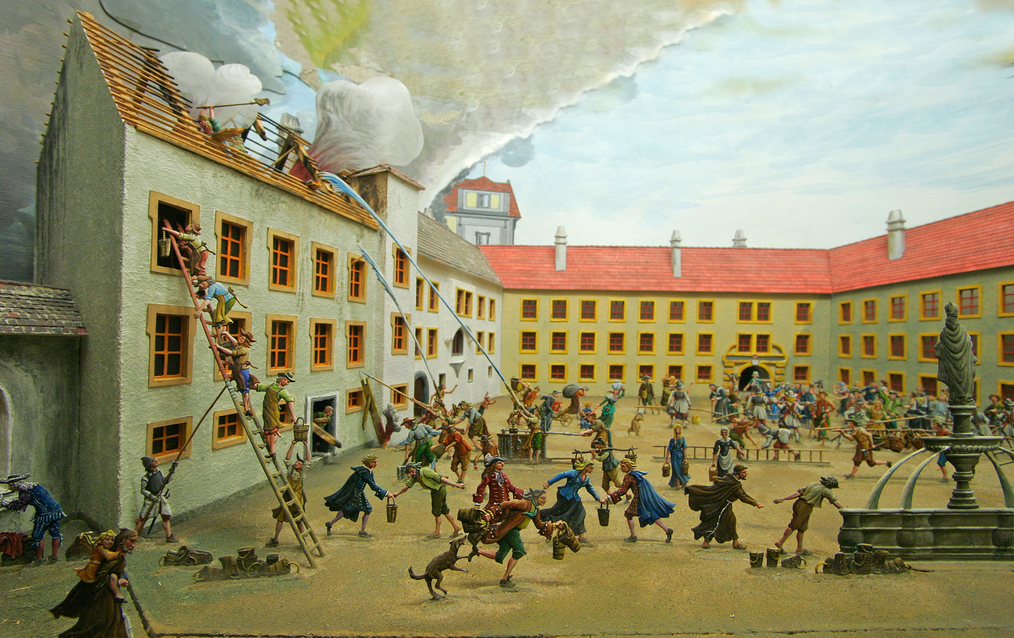 Diorama of a historical fire department scene with pewter figures in a courtyard.