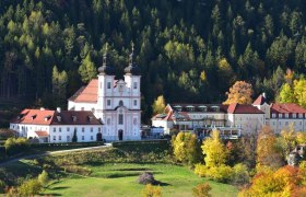 The Maria Schutz pilgrimage church in front of a wooded hill in the fall.