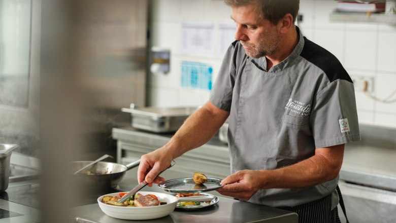 A chef prepares a dish in a restaurant kitchen.