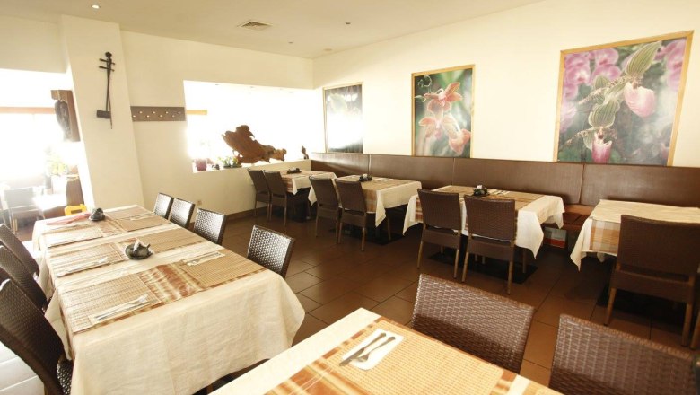 Interior view of a restaurant with laid tables and flower pictures on the wall.