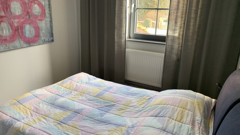 Bedroom with bed, colorful ceiling, window and artwork on the wall.