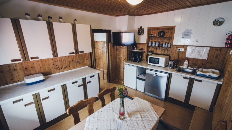 Cozy kitchen with wooden walls, white cabinets, dining table and modern appliances such as microwave and dishwasher.