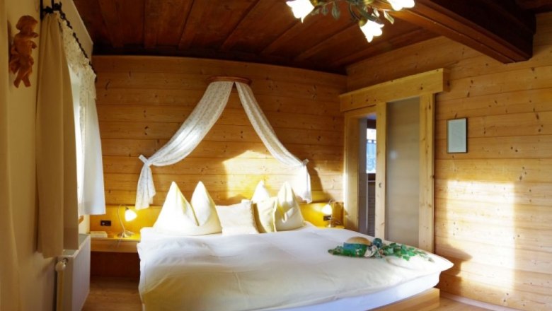 Cozy bedroom with wooden walls and double bed.