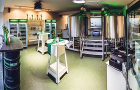 Interior view of a small brewery with stainless steel kettles and fridges full of drinks.