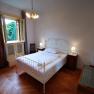 Bedroom with double bed, bedside tables and open window with a view of the trees.