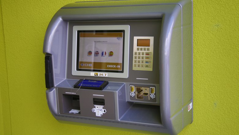 A check-in machine on a green wall.