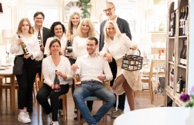 Group of people in a room with bottles of wine.