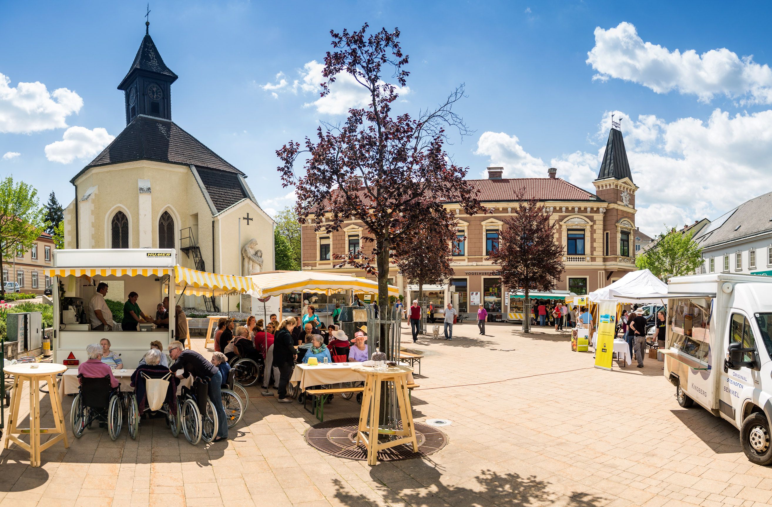 Market square in Gloggnitz with church, stalls and people.