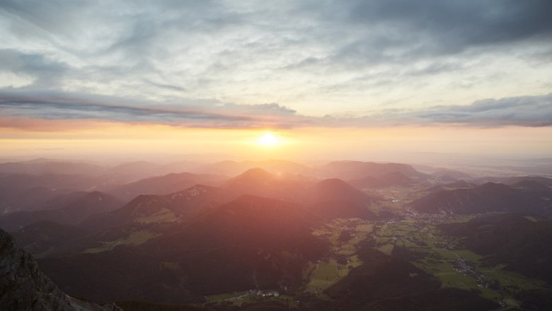 Sunset over a mountain landscape with clouds and valleys.