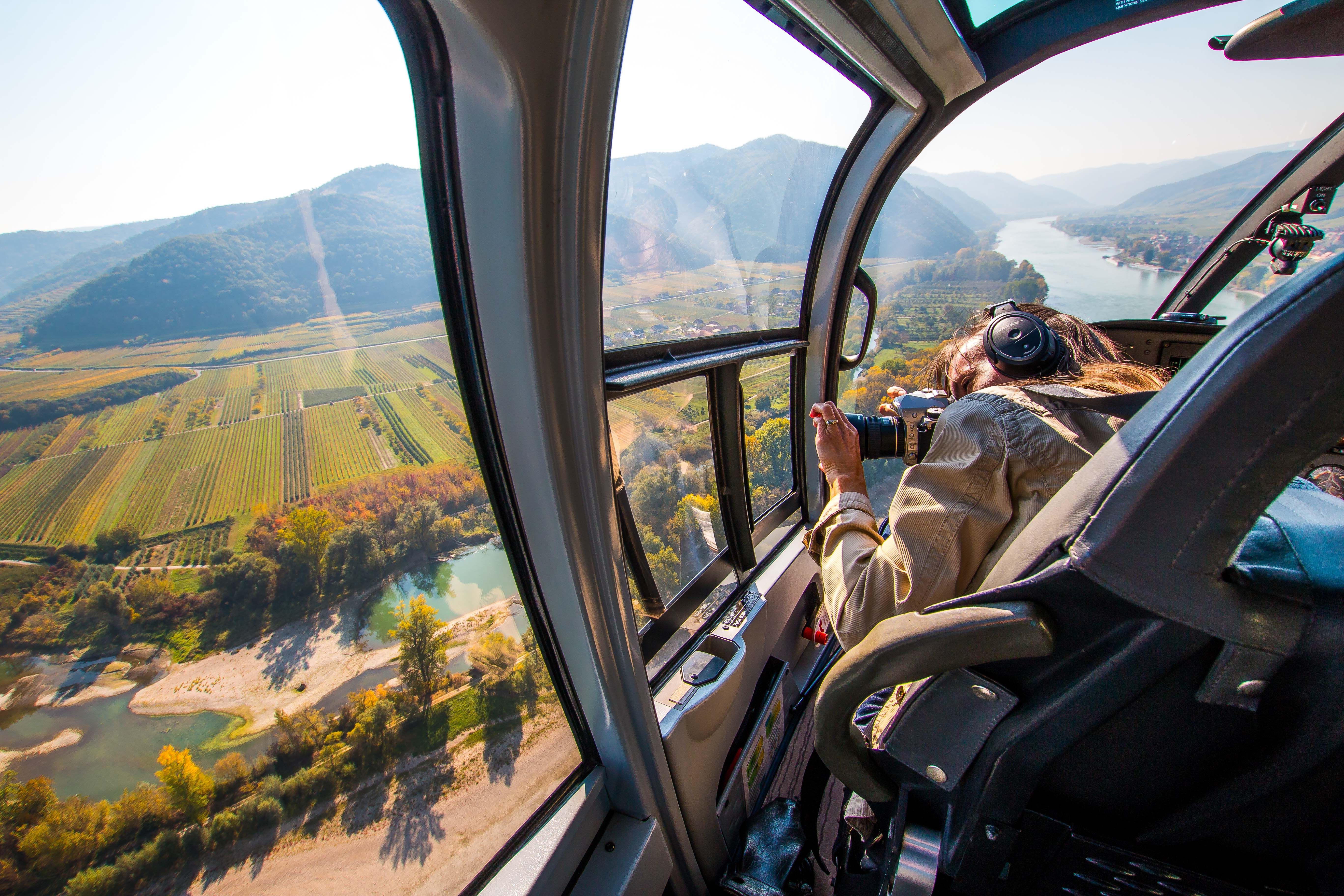 View from a helicopter of a landscape with a river and fields.