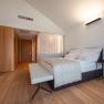 Modern hotel room with large bed, wooden floor and minimalist furnishings.