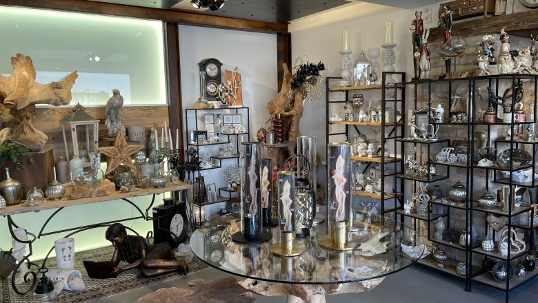 Interior view of a decoration store with shelves full of decorative items and a table with a glass top.