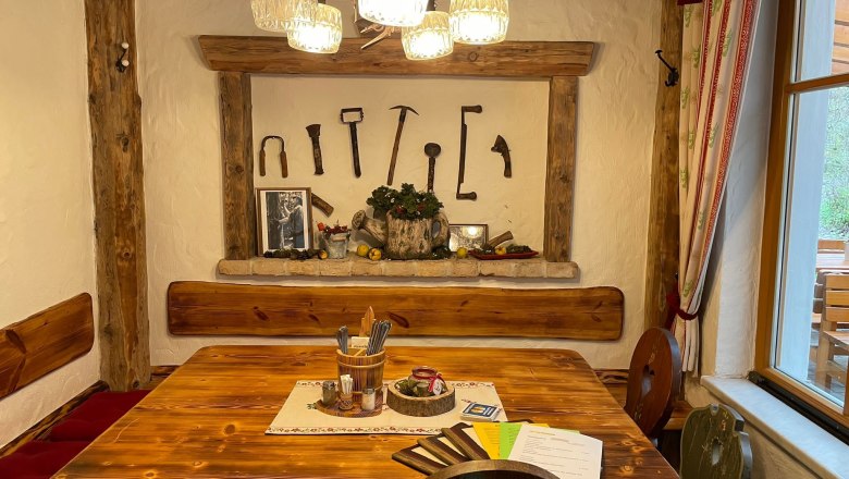 Rustic guest room with wooden table, wall decorations made from old tools and cozy lighting.