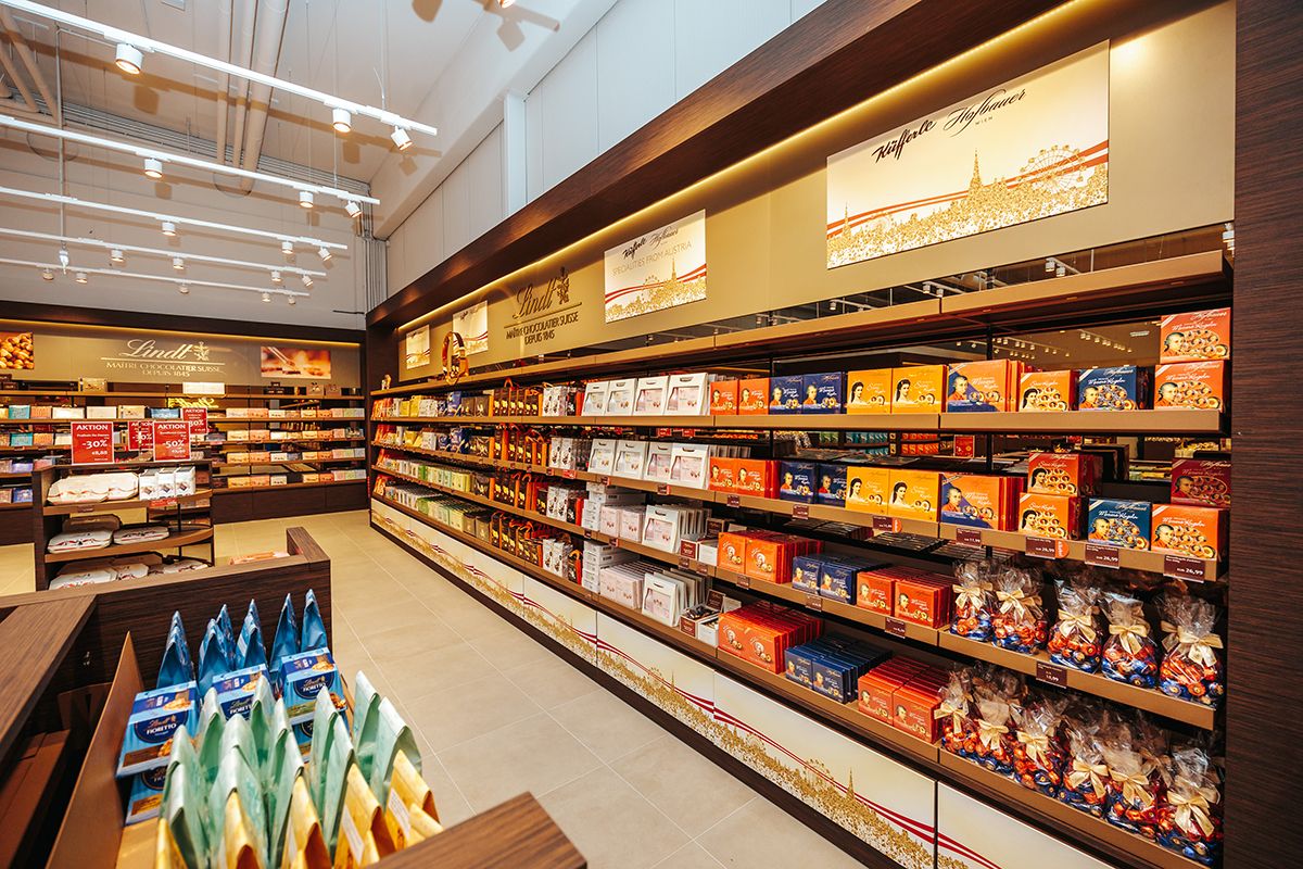 Interior view of a Lindt & Sprüngli store with shelves full of chocolate and sweets.