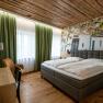 Modern guest room with double bed, wooden floor and green curtains.