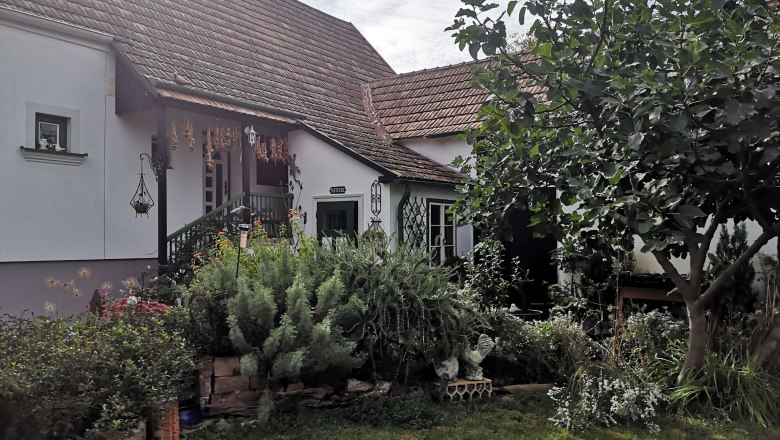 A cozy house with a garden, surrounded by plants and a tree.