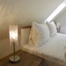 Cozy bedroom with sloping ceiling, bed and bedside lamp.