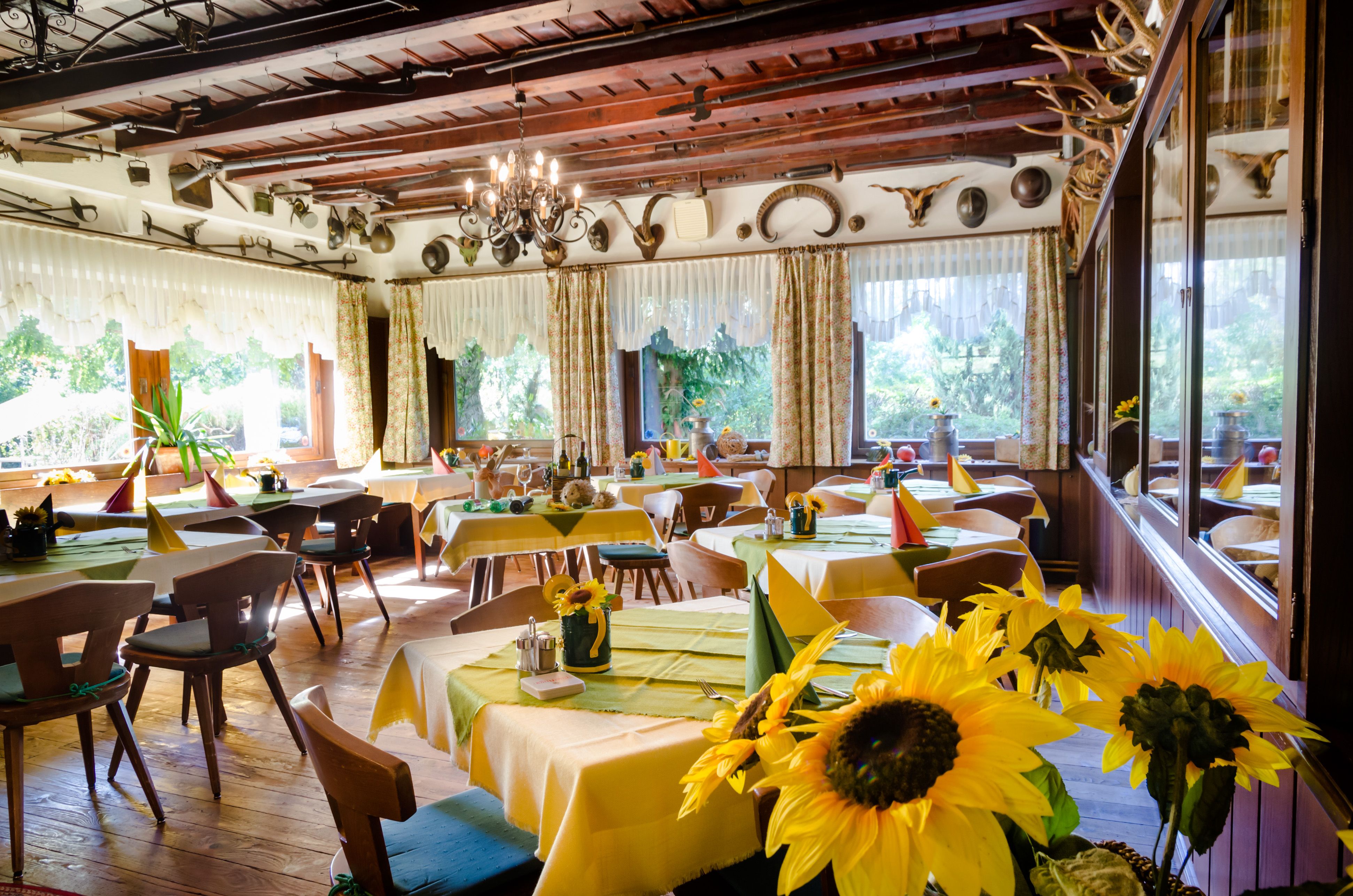 Cozy dining room with wooden furniture, yellow tablecloths and sunflowers.