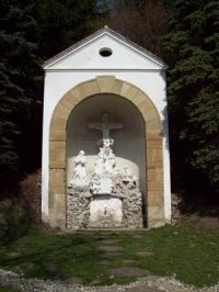 A small chapel with a cross and religious figures in a niche.