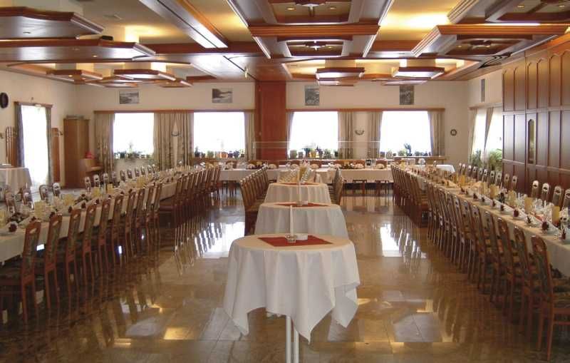 A large, elegantly decorated hall with long, laid tables and seating for over 200 people.