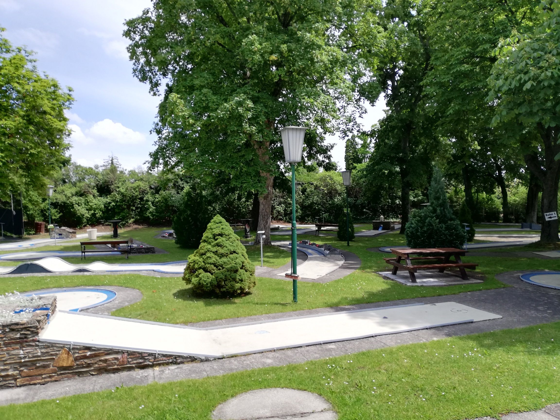 Minigolf course with trees and benches in a park.
