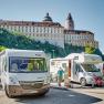 Motorhome parking area with motorhomes in front of Melk Abbey in Austria.