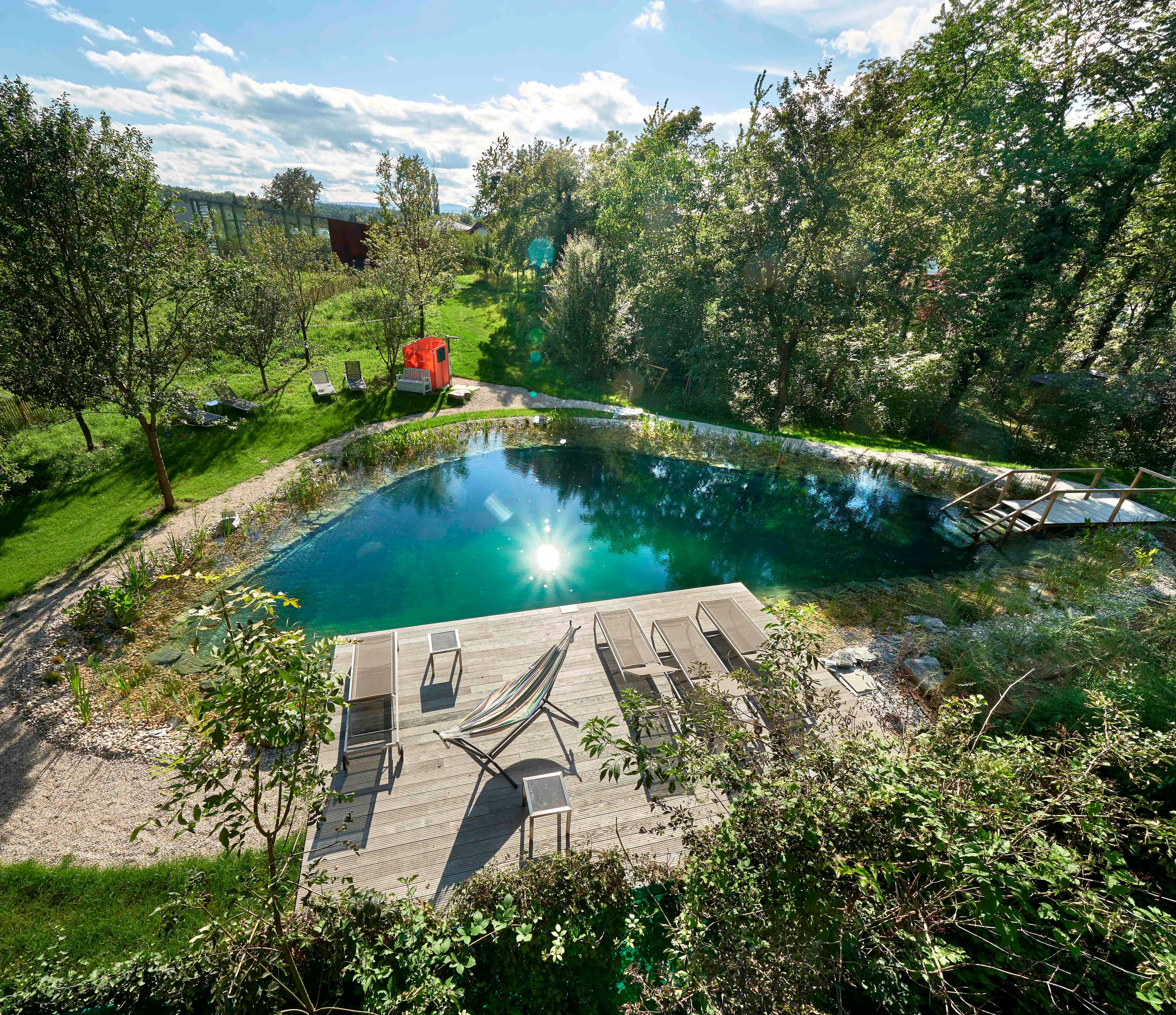 Modern wooden garden lofts with pond and plants in the foreground.