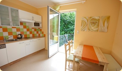 Kitchen and dining area, © Patrizia Schiller Bright kitchen with dining area, colorful tiled backsplash and open balcony door.