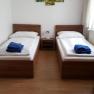 Two single beds in a room with wall decoration and blue towels.