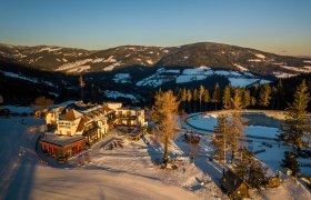 Alpengasthof Enzian in a snowy mountain landscape at sunset.