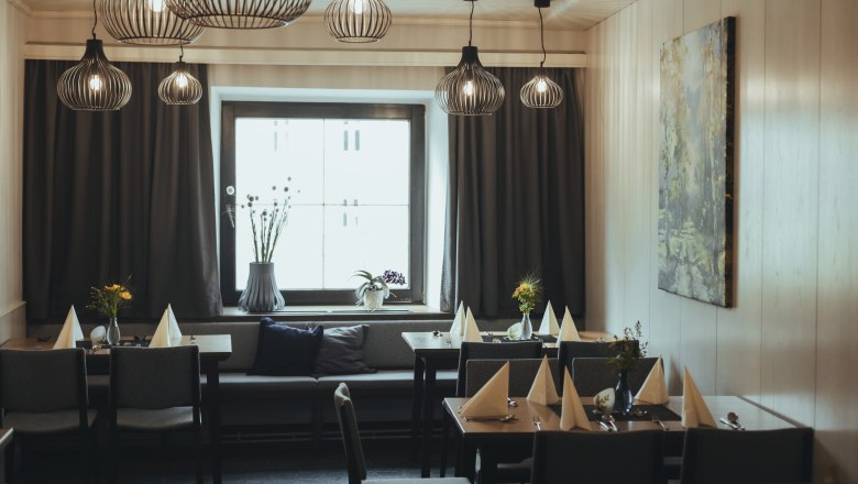 Modernly furnished guest room with stylish lamps, laid tables and a large window.